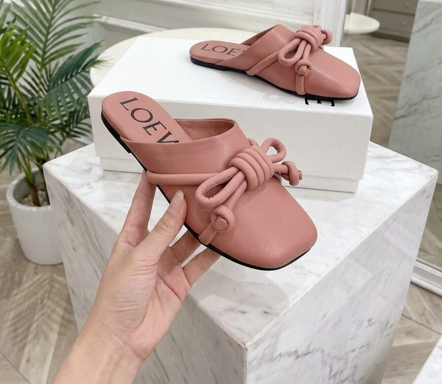 Close-up of elegant Pink velvet flat shoes placed on stones, Shoeaholic Bahrain Footwear. || لقطة قريبة لحذاء نسائي مسطح مخملي باللون العنابي على الأحجار، شوهوليك البحرين للأحذية.